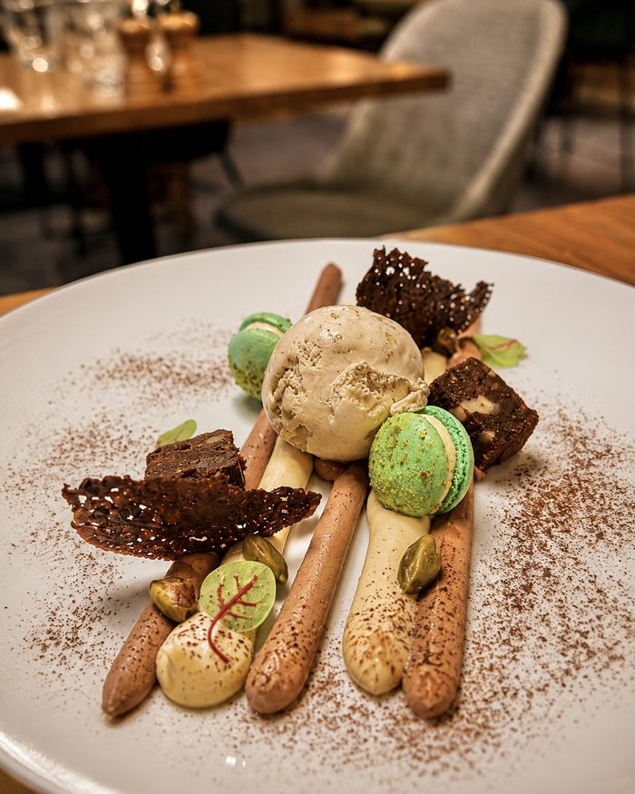 Un dessert à la pistache, macarons et tuiles au chocolat, au restaurant de l’hôtel