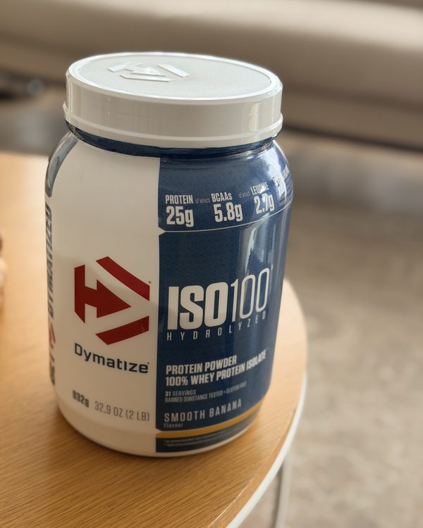 Le pot de whey Dymatize ISO100 sur la table basse en bois