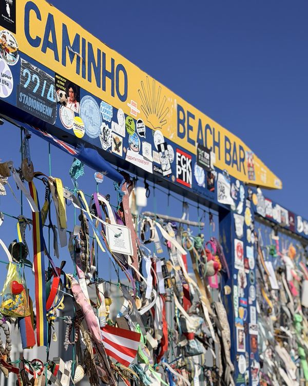 Panneau Caminho Beach Bar couvert de rubans et d’autocollants laissés par les pèlerins