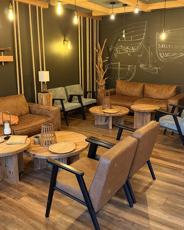 Le salon de l’hôtel, fauteuils en cuir, tables en bois et dessins de bateaux au mur