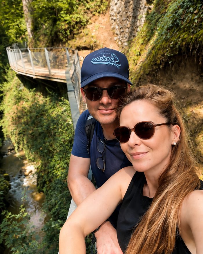 Selfie d’Amélie et de son compagnon sur une passerelle, au-dessus d’une gorge boisée