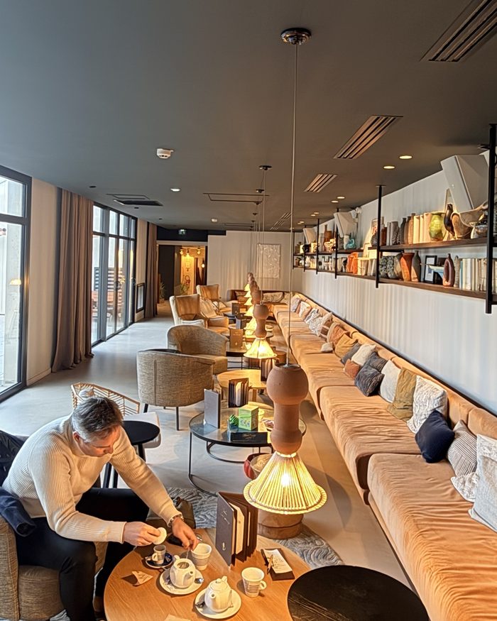 Le grand salon de l’hôtel, avec sa longue banquette, ses suspensions en terre cuite et ses étagères de céramiques