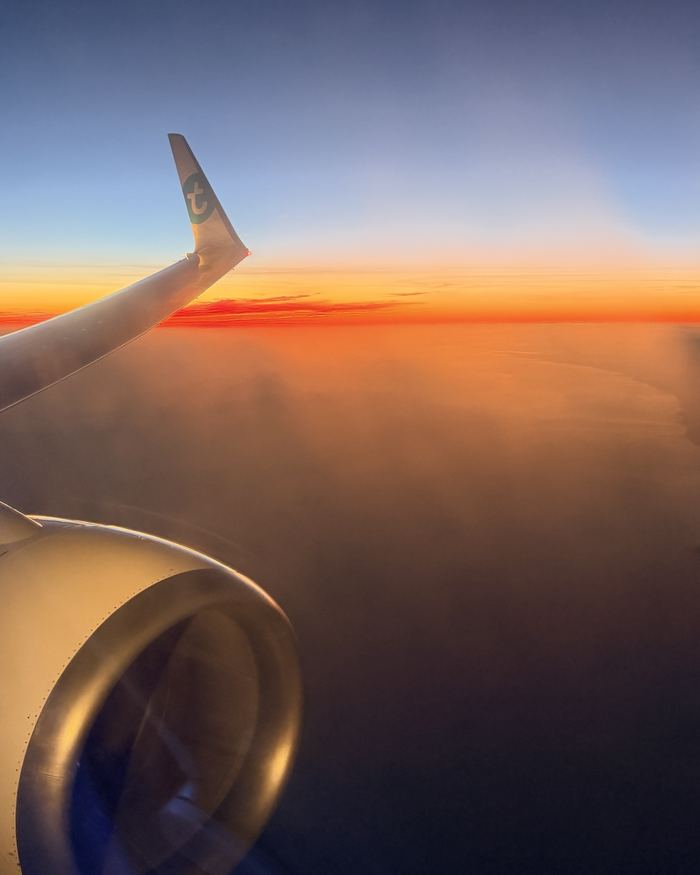 Aile d’avion Transavia au-dessus des nuages au lever du soleil