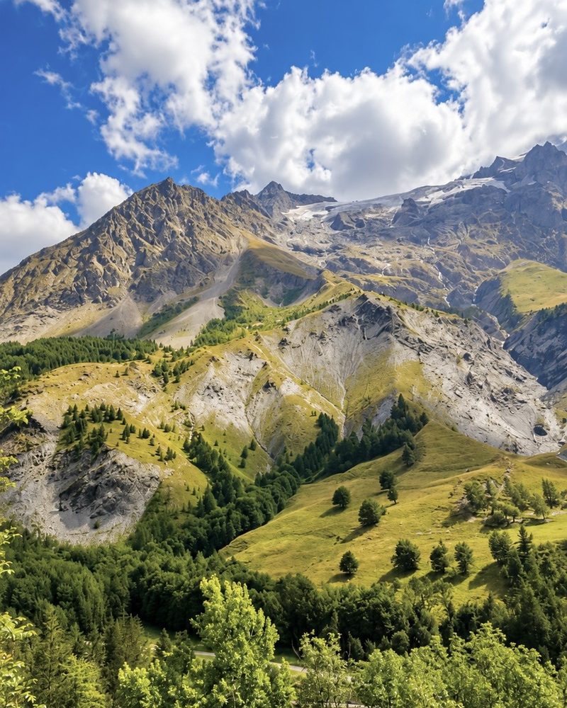 Les montagnes et le glacier de La Grave au-dessus des alpages et des forêts, sous un ciel bleu